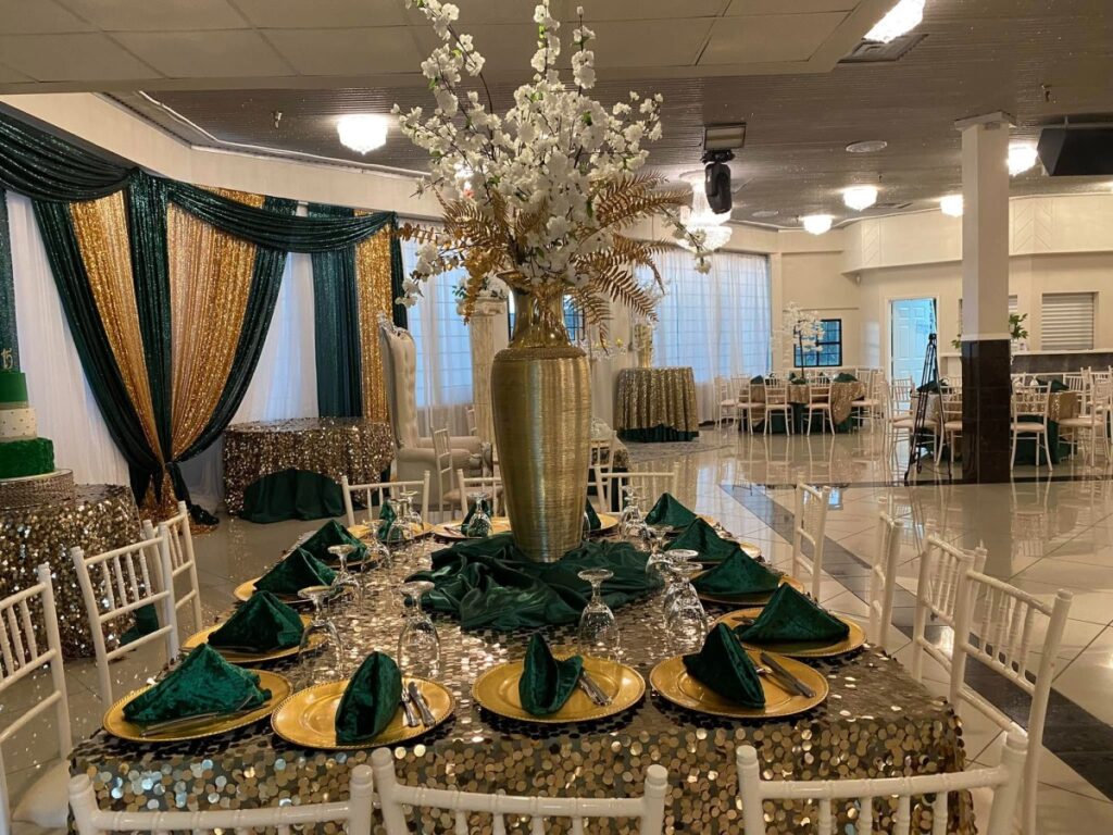 Elegant wedding reception table with gold and green decor.